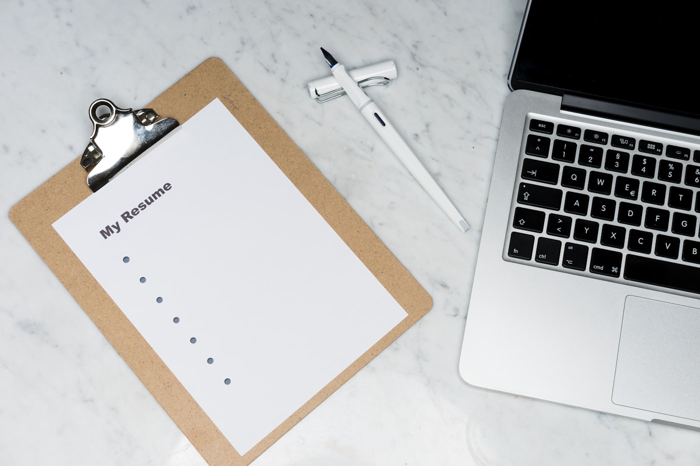 A printed resume on a clipboard beside a laptop keyboard